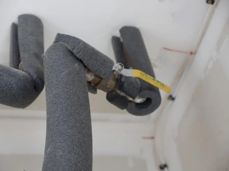 Insulated water heater pipes with foam padding and a yellow valve, installed by Water Heaters Masters Inc. in a Vacaville residence.