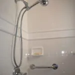 Image of a newly installed shower with a chrome showerhead and grab bar, completed by We Love Small Jobs Handyman Services-Remodelers & Builders in Oakland.