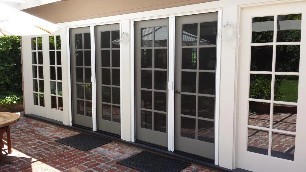 A set of sliding patio doors with grid patterns and screen doors on a brick patio, installed by Wesco Screen Company Inc. in San Rafael.