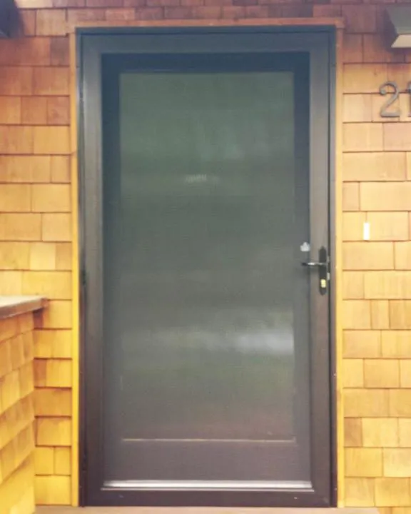 A screen door installed in a wooden-framed doorway, crafted by Wesco Screen Company Inc. in San Rafael.