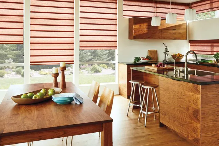 A modern kitchen with wooden interiors featuring red Roman shades from Wesco Screen Company Inc., providing a seamless blend of style and privacy.