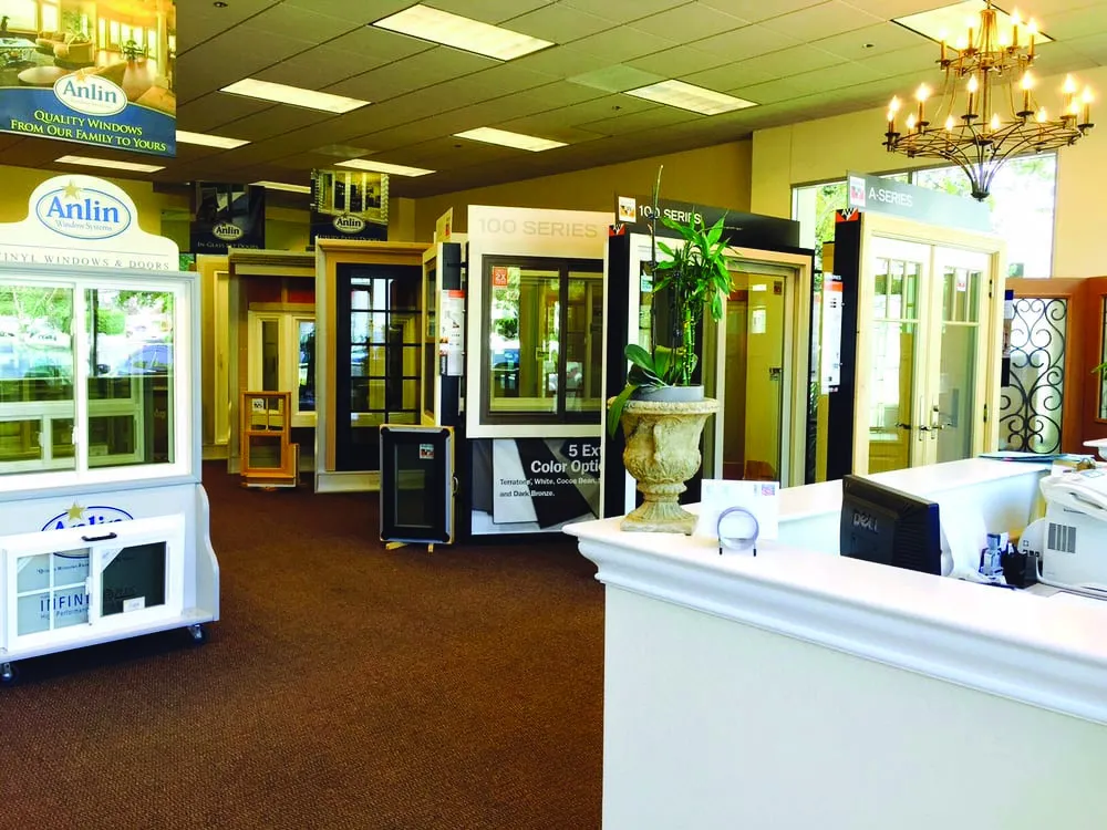 Interior view of a showroom in Concord featuring various window and door displays at West Coast Windows and Doors, Inc., with a chandelier and office desk in the foreground.