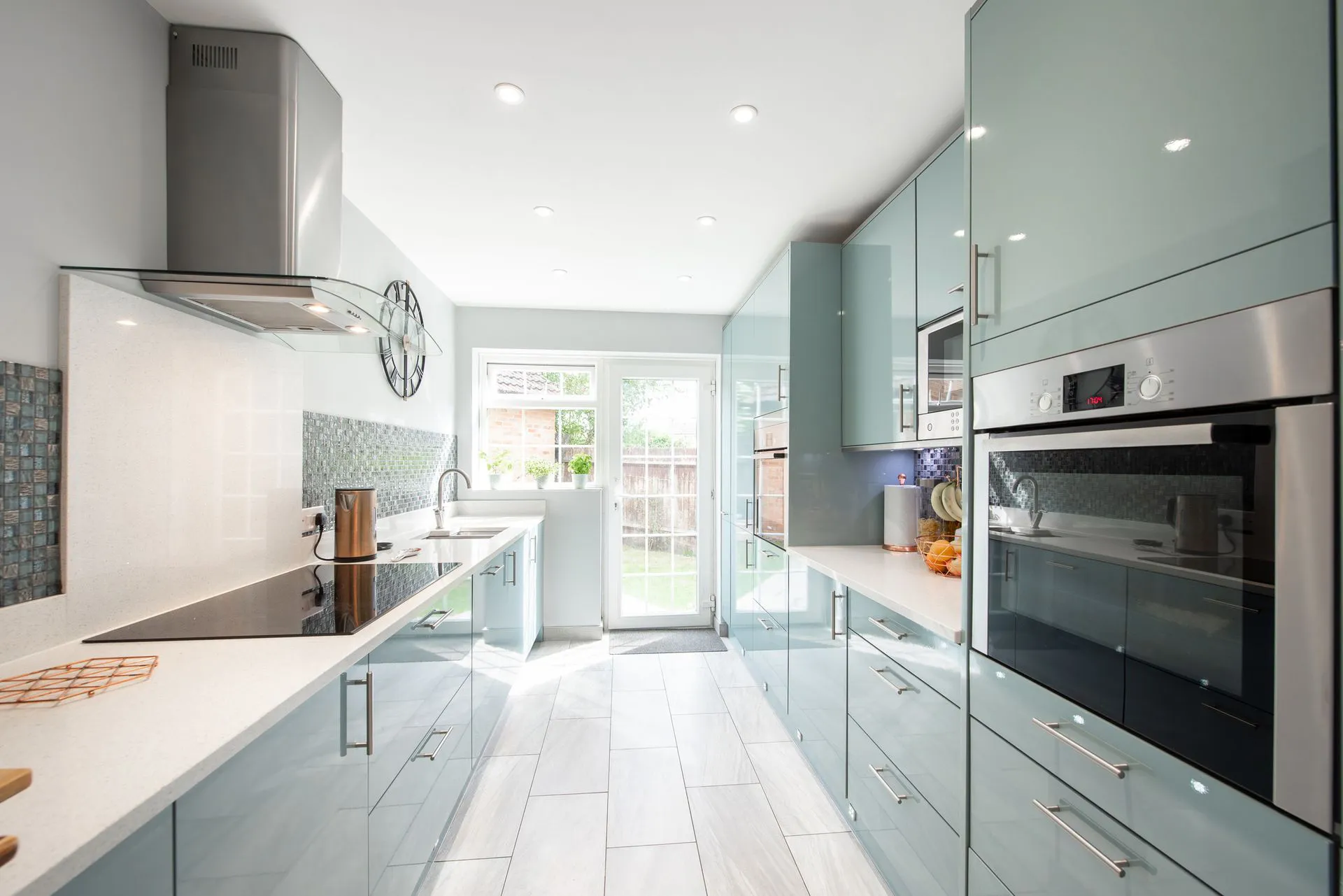 A modern kitchen with sleek cabinetry and a large glass door leading to a garden, designed by West Coast Windows and Doors, Inc. in Concord, showcasing a bright and contemporary style.