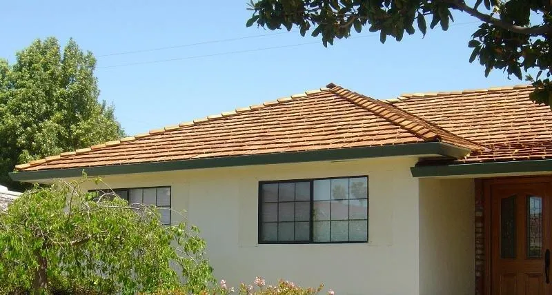 A house with a new wooden shingle roof installed by Westshore Roofing, Inc. in San Jose, surrounded by trees and a clear blue sky.