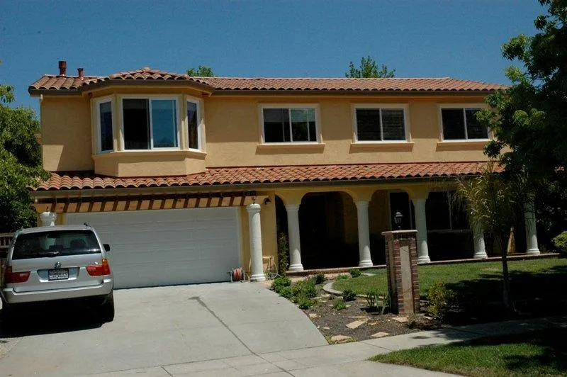 A two-story house in San Jose with a tiled roof installed by Westshore Roofing, Inc., featuring an attached garage and a car parked in the driveway.