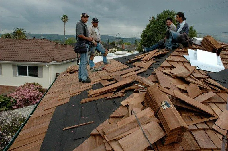 A team of workers from Westshore Roofing, Inc. installing wooden shingles on a residential roof in San Jose under a cloudy sky.
