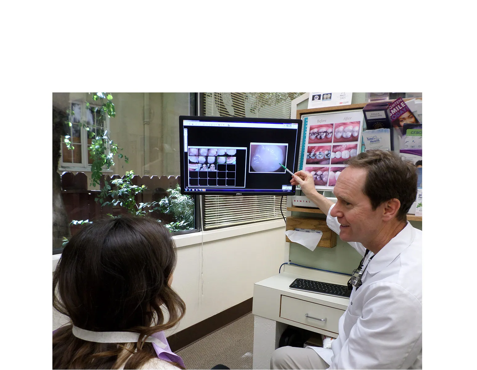 A dentist at William R. Hummer, DDS in San Leandro explaining dental X-rays on a computer screen to a patient in an office setting.