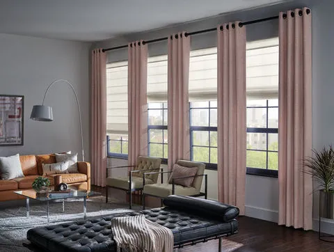 A modern living room featuring soft blush curtains and sleek black window frames. The decor includes a leather sofa, armchairs, and a chaise lounge, highlighting Window-ology's design solutions in Pleasanton.