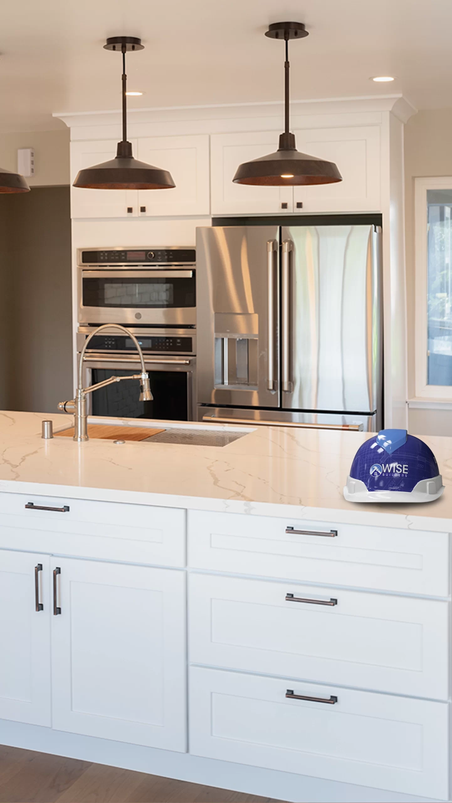 A modern kitchen with a stainless steel fridge, built-in ovens, marble countertop, and a blue Wise Builders Remodeling, Inc. hard hat in San Francisco.