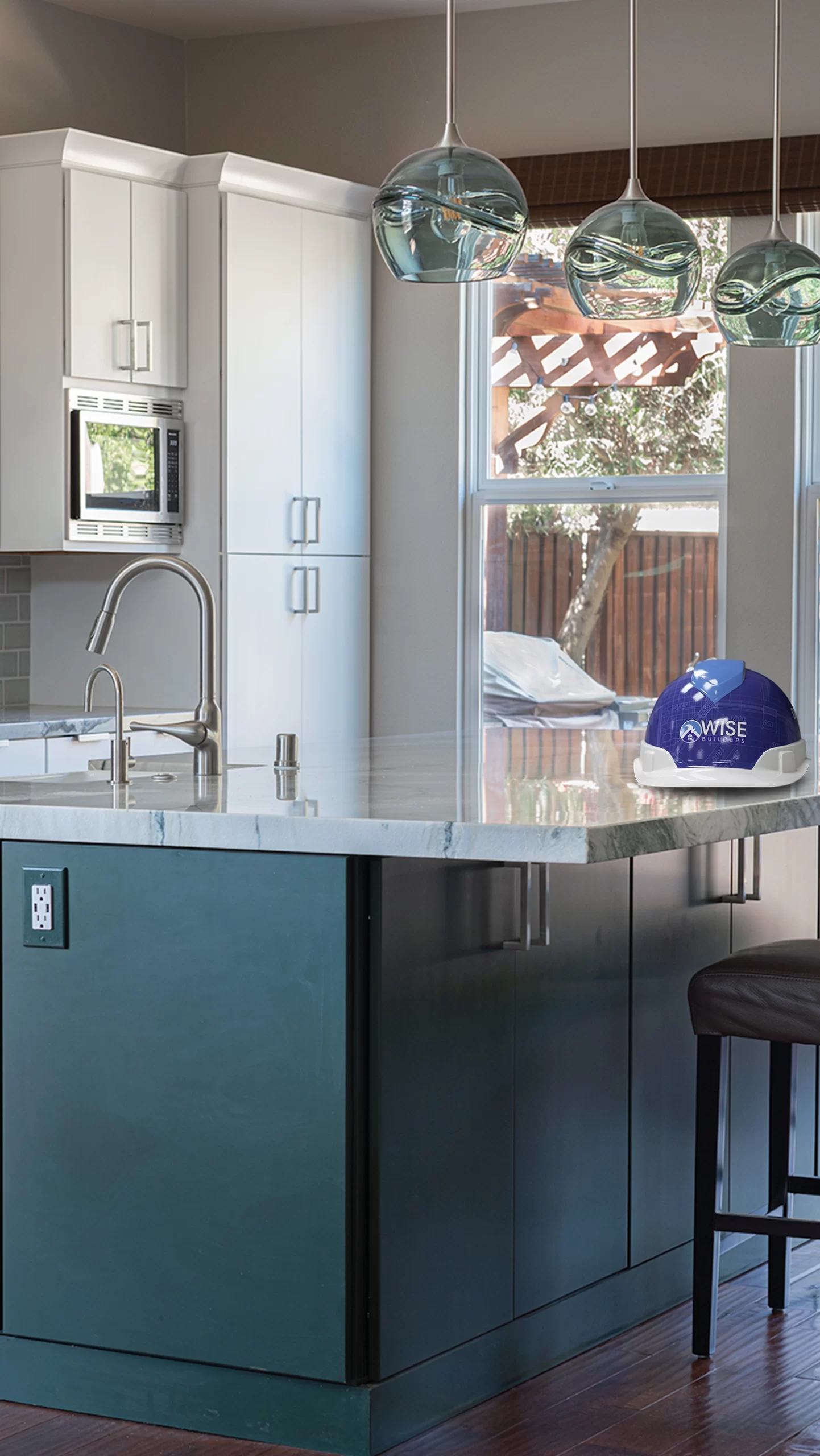 A remodeled kitchen in San Francisco featuring a modern countertop, sleek faucet, and three pendant lights, with a helmet branded "Wise Builders Remodeling, Inc." on the counter.