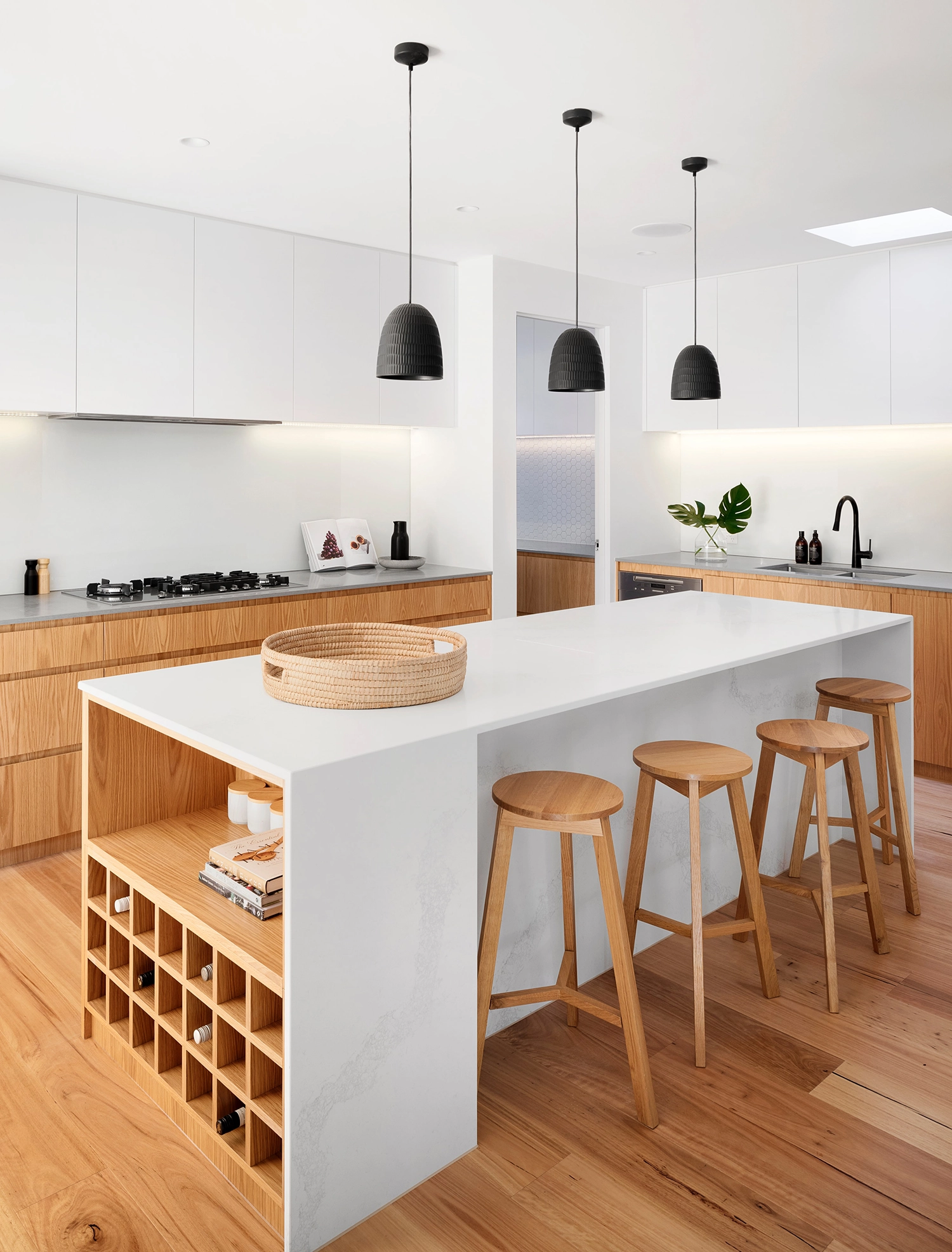 A modern kitchen with a white countertop island, wooden stools, hanging lights, and sleek cabinetry, designed by Wise Builders Remodeling, Inc. in San Francisco.