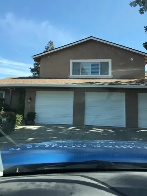 A house in Livermore with a well-maintained roof, serviced by Yorkshire Roofing of Northern California Inc. DBA Roofmax, viewed from inside a vehicle.
